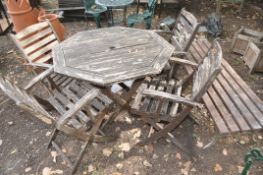 A SLIGHTLY DISTRESSED OCATAGONAL GARDEN TABLE , four similar folding chairs, a cast iron bases