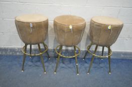 A SET OF THREE LIGHT BROWN UPHOLSTERED STOOLS, on four cylindrical brassed legs, with a foot rest,