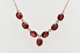 A YELLOW METAL RED PASTE NECKLACE, comprising a series of oval cut red pastes, with a similarly
