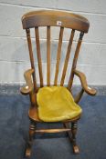 A REPRODUCTION OAK CHILDS ROCKING CHAIR, with a later fabric seat pad, width 41cm x depth 67cm x