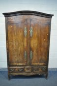 A 19TH CENTURY FRENCH FRUITWOOD ARMOIRE, having two shaped doors, enclosing an empty interior,