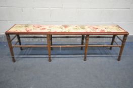 AN EDWARDIAN MAHOGANY LONG STOOL, with a floral fabric top, on eight turned legs, united stretchers,