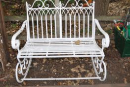 A MODERN WROUGHT IRON ROCKING GARDEN BENCH with scrolled detail to ends, shaped metal seat width