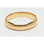 A YELLOW METAL BANGLE, a foliage engraved, hollow yellow metal oval hinged bangle, fitted with a