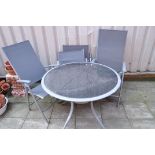 A METAL FRAMED AND SMOKED GLASS GARDEN TABLE diameter 100cm and four similar folding chairs (