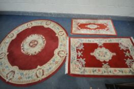 A RED GROUND CIRCULAR RUG, with cream border and centre, diameter 185cm, and two similar rectangular