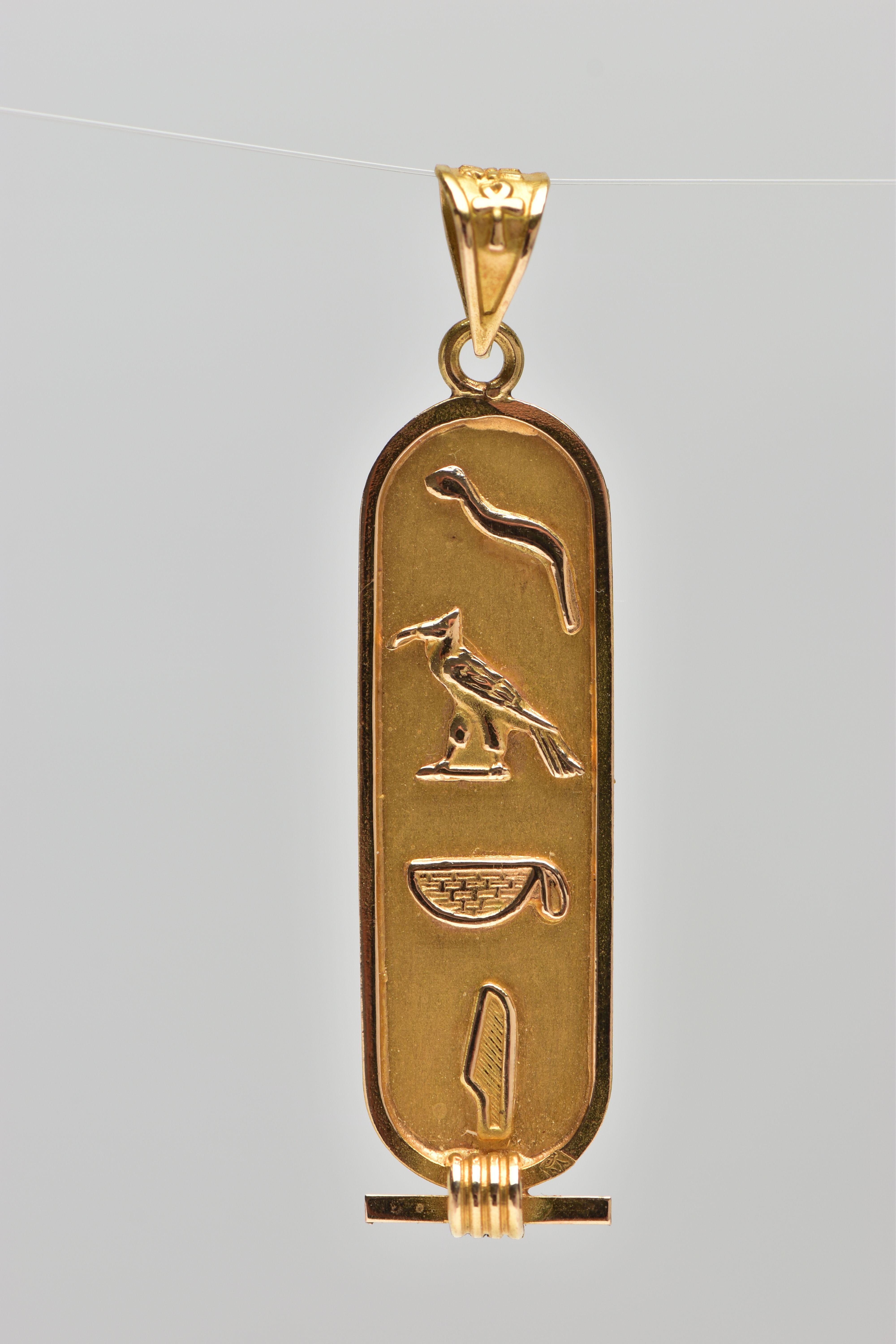 A YELLOW METAL EGYPTIAN CARTOUCHE PENDANT, of an oval outline displaying hieroglyphics, fitted