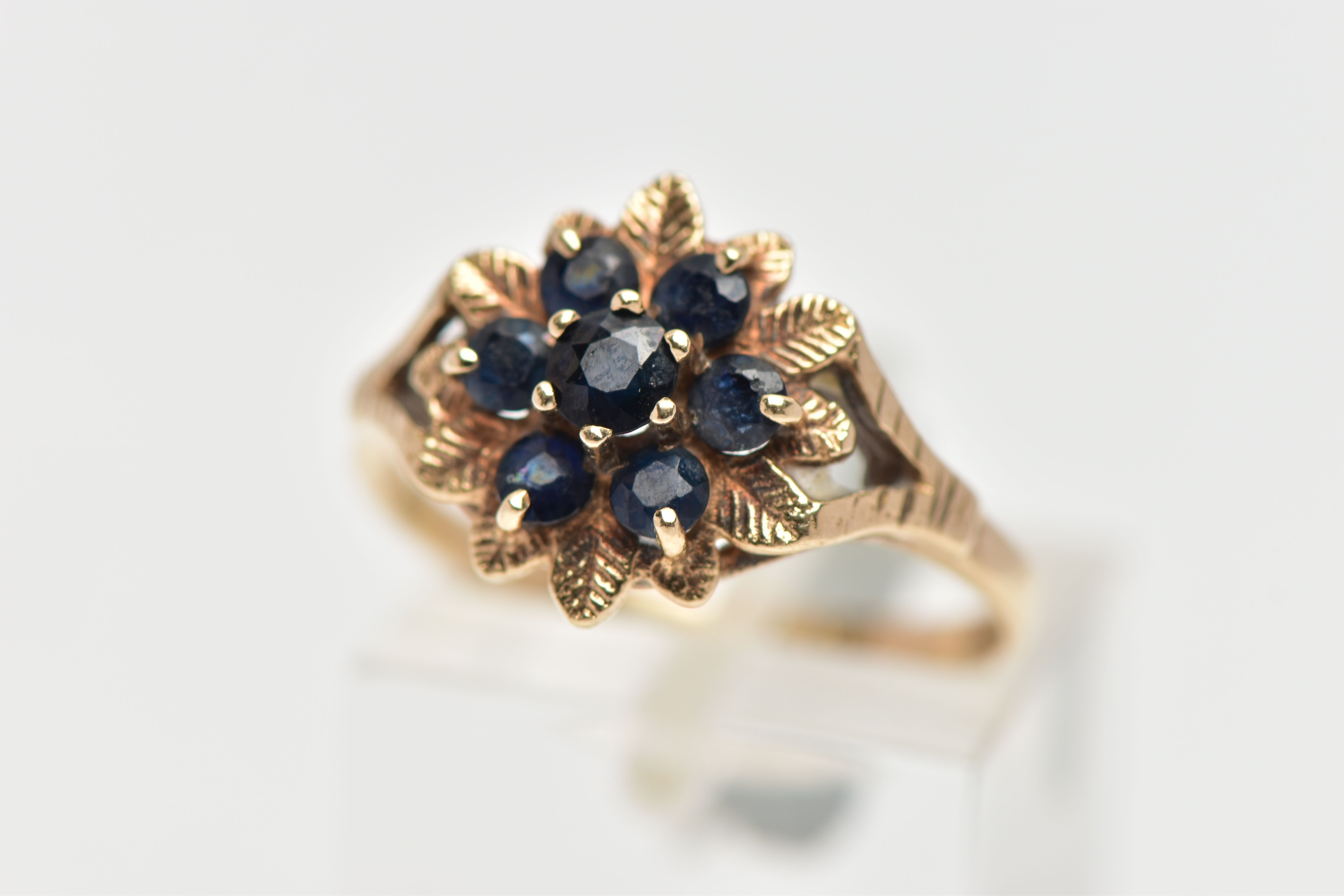 A 9CT GOLD SAPPHIRE CLUSTER RING, flower shape cluster set with seven circular cut deep blue