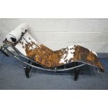 IN THE MANNER OF LE CORBUSIER, a cow hide lc4 chaise longue, with a chrome frame, on a metal frame