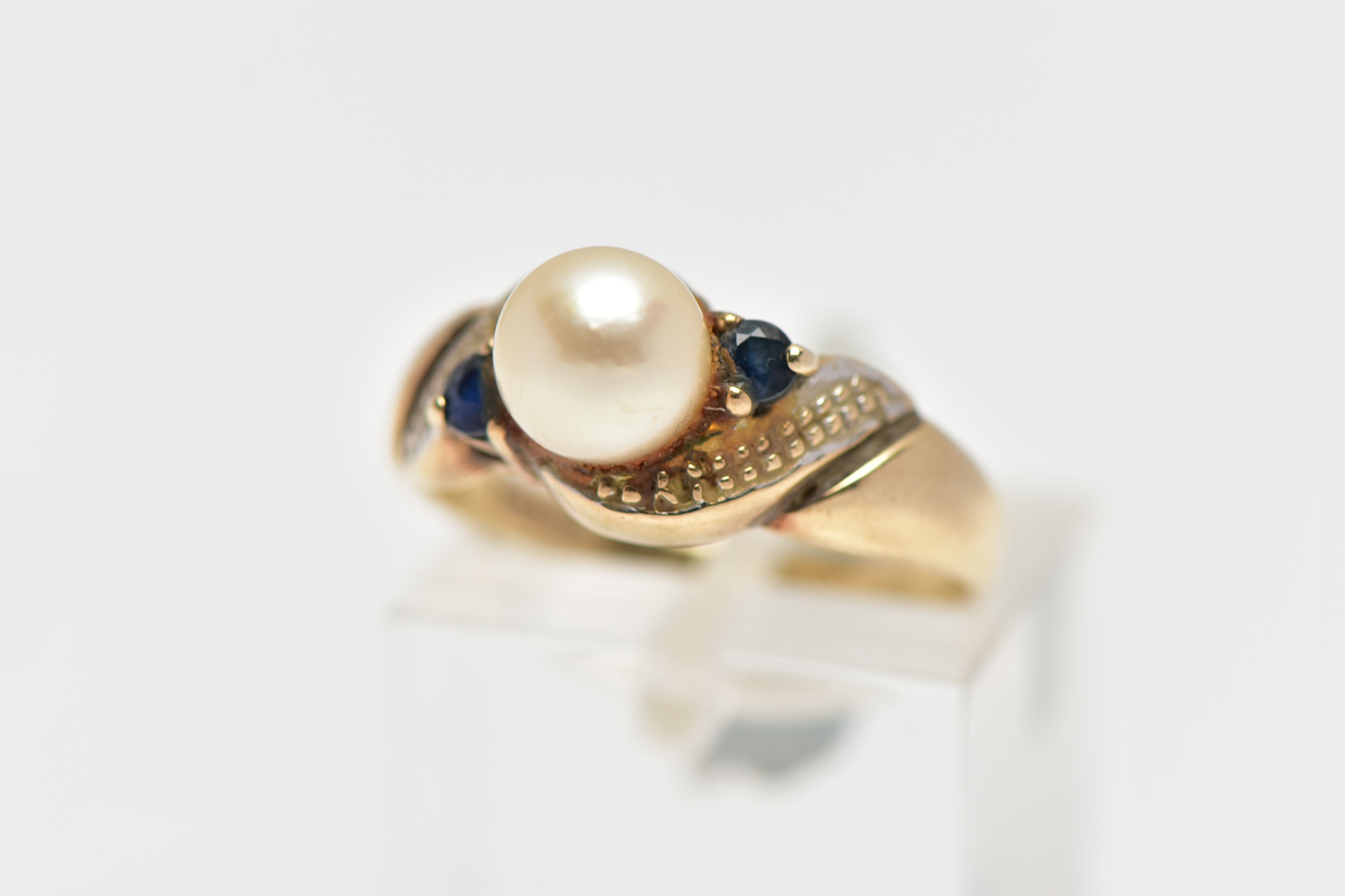 A 9CT GOLD CULTURED PEARL AND SAPPHIRE RING, centring on a single cultured cream pearl with a pink