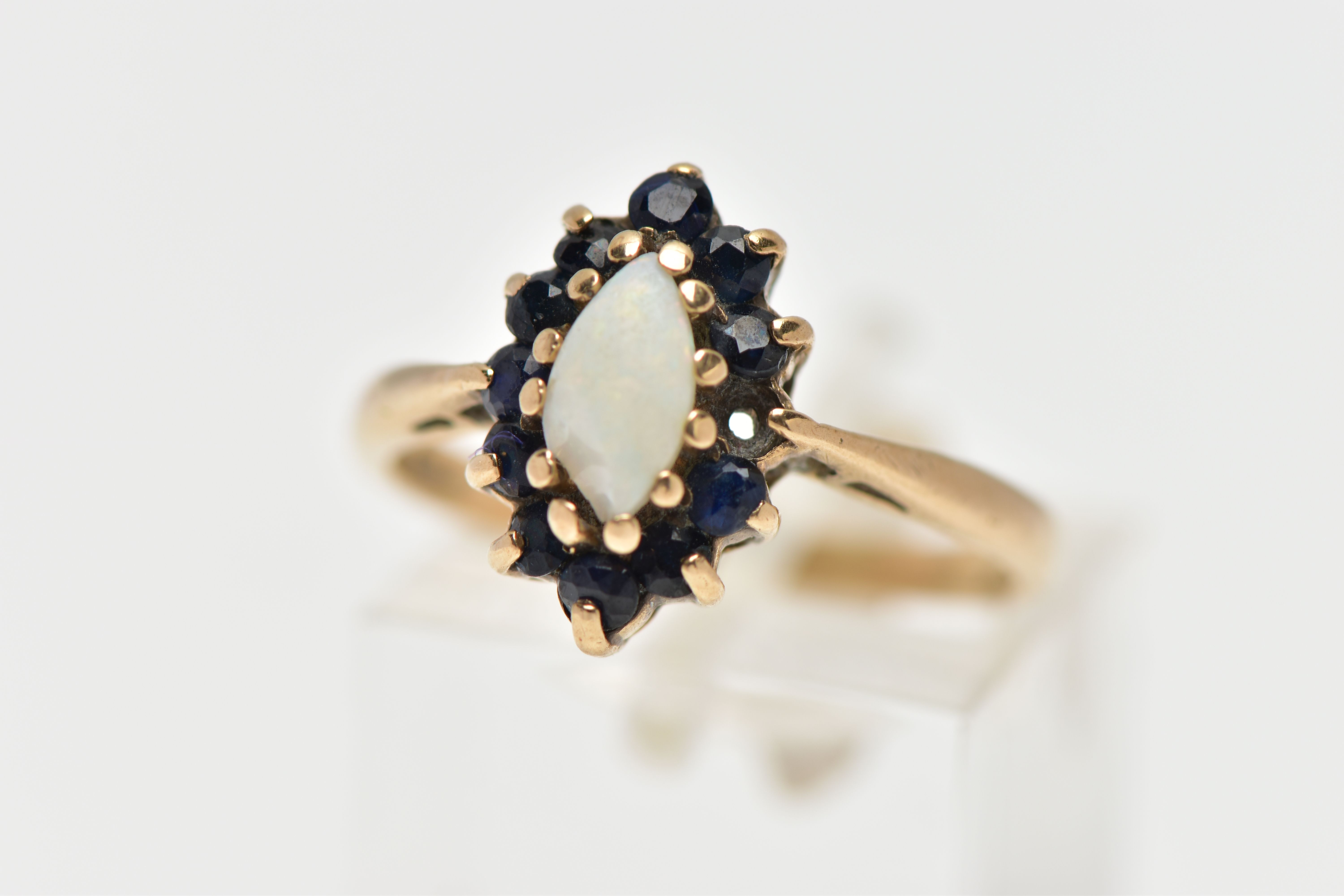 A 9CT GOLD OPAL AND SAPPHIRE CLUSTER RING, the marquise opal cabochon, with circular cut sapphire
