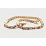 A 9CT YELLOW GOLD DIAMOND AND RUBY LINE BRACELET, set with approximately thirty one round