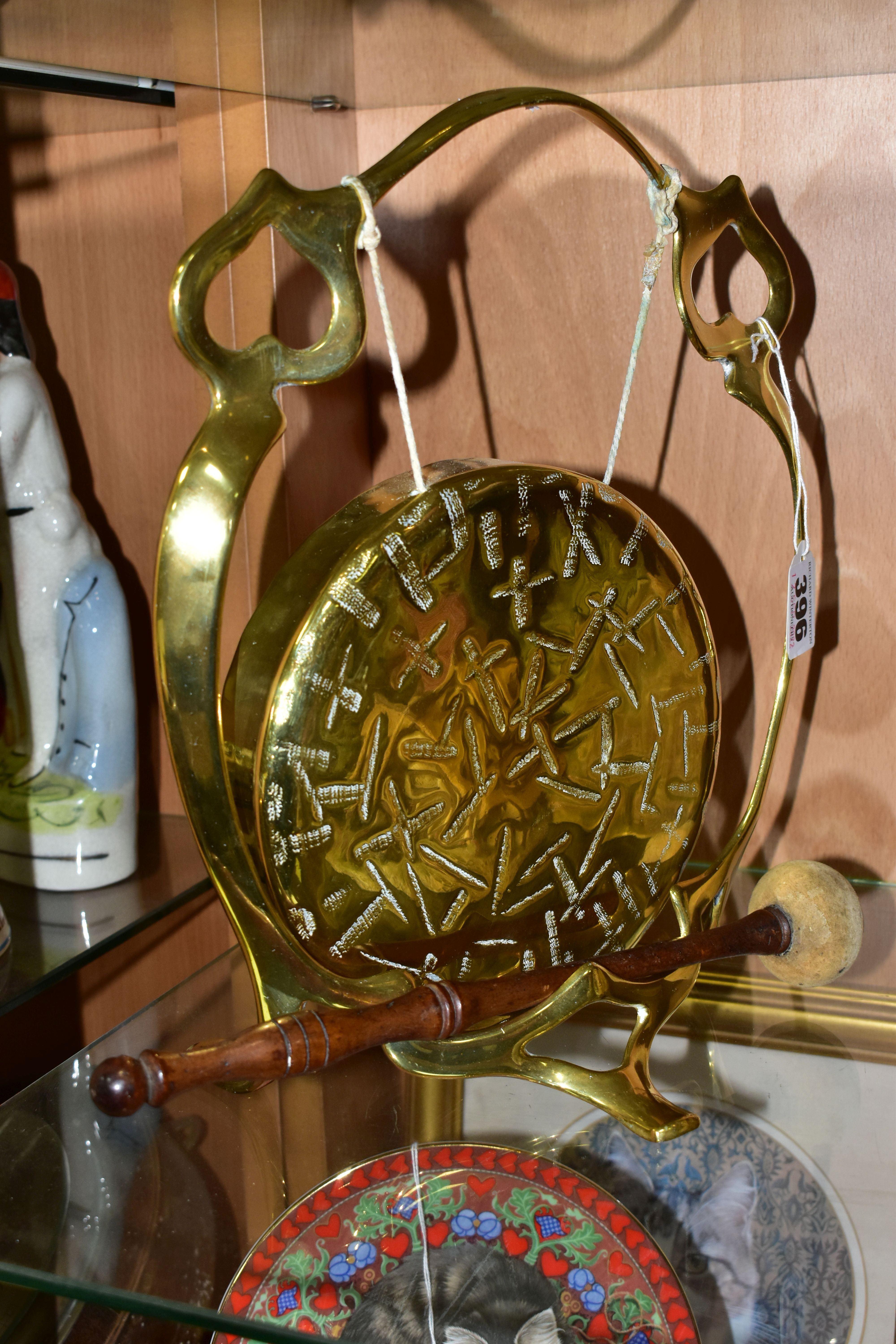 A BRASS TABLE GONG, suspended from a brass frame, with wooden handled beater, frame is stamped