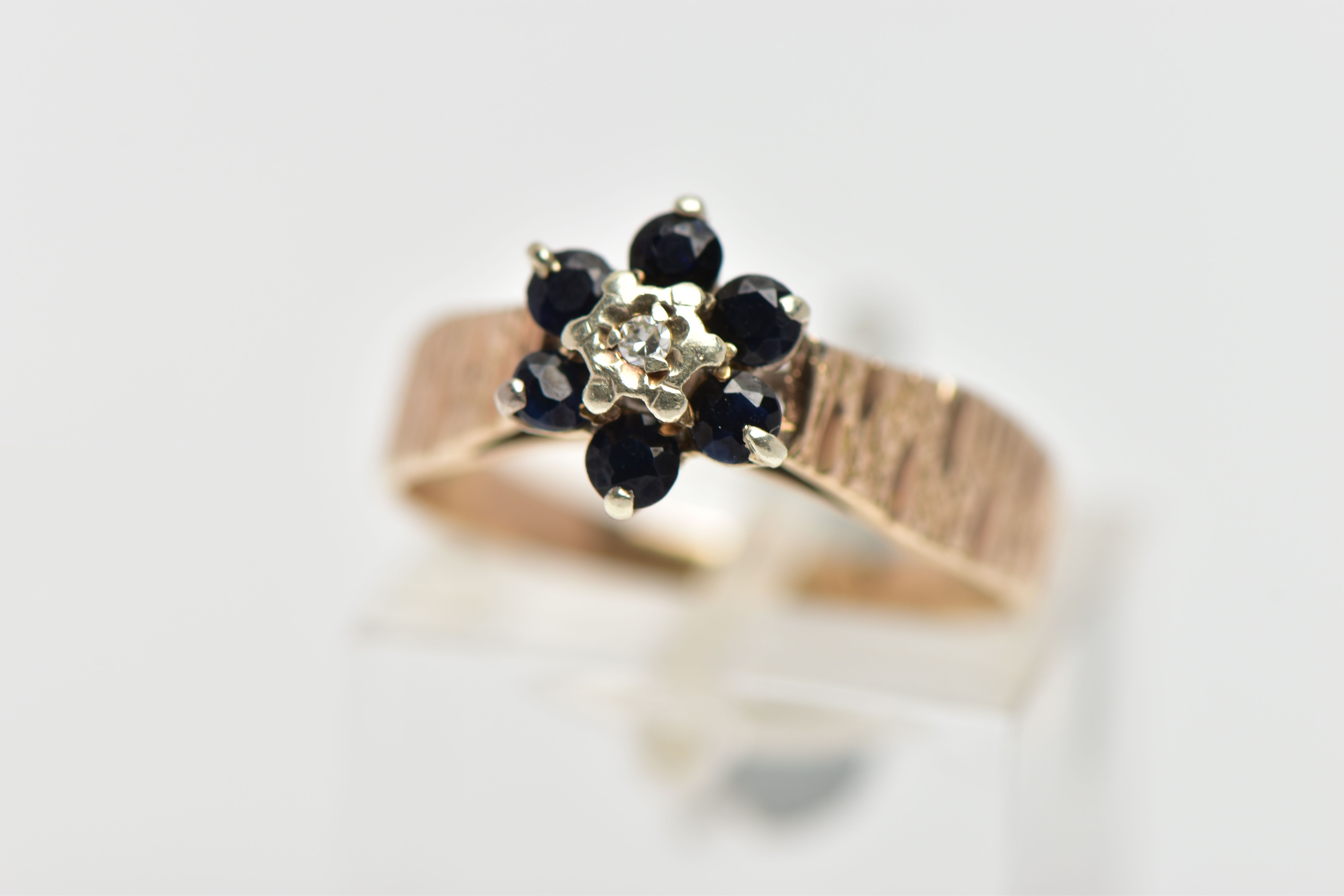 A 9CT GOLD SAPPHIRE AND DIAMOND CLUSTER RING, centring on an illusion set, single cut diamond,