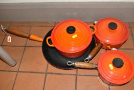 FOUR PIECES OF LE CREUSET CAST IRON COOK WARE, all with orange enamel finish, comprising a twin