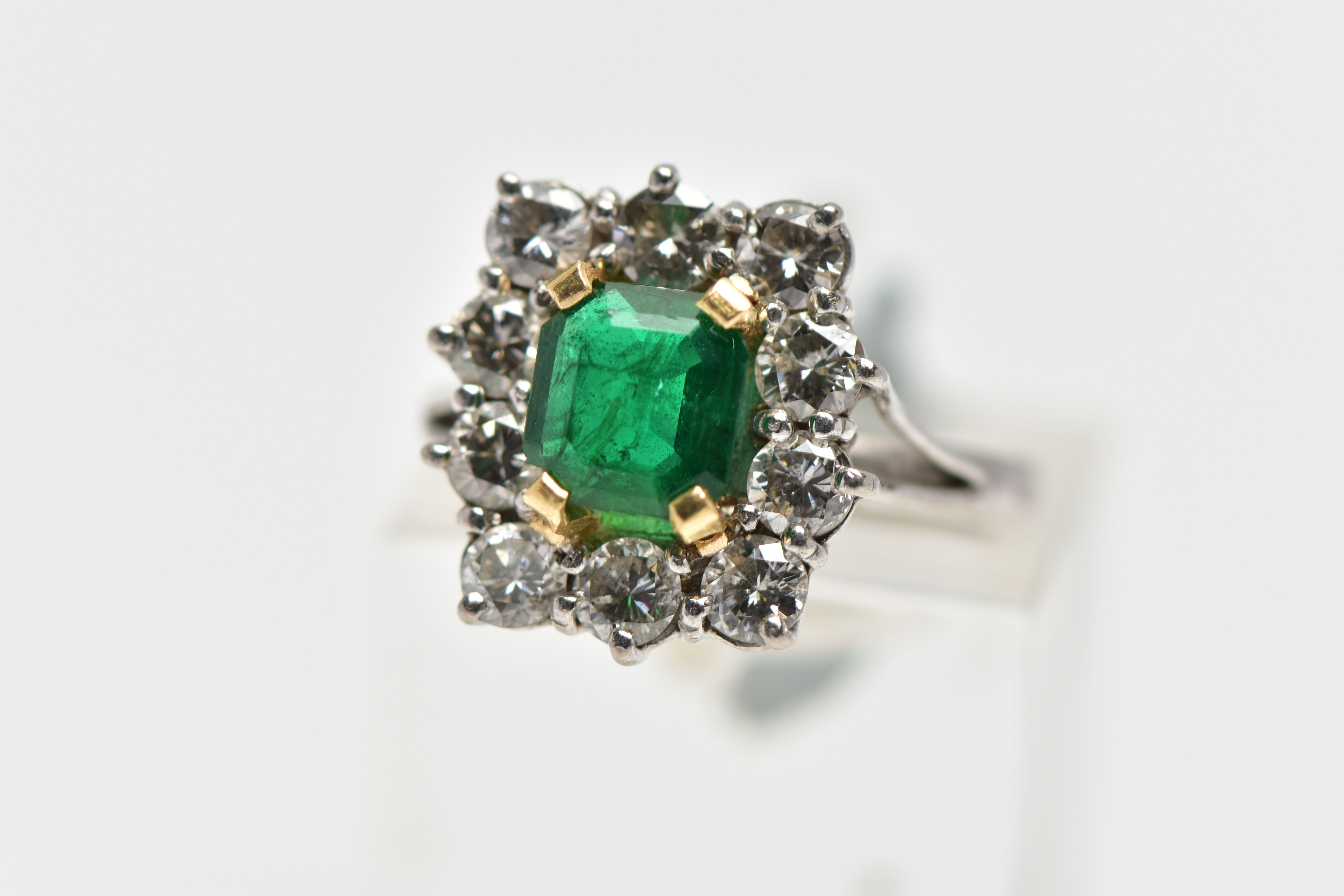 AN 18CT WHITE AND YELLOW GOLD EMERALD AND DIAMOND CLUSTER RING, the rectangular cut emerald,