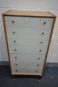 A MID CENTURY OAK G PLAN E GOMME CHEST OF SEVEN DRAWERS, on ebonised legs, and brass feet, width