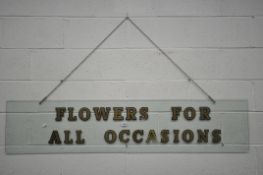 A RECTANGULAR GLASS SIGN, READING 'FLOWERS FOR ALL OCCASIONS', length 168cm x height 36cm (