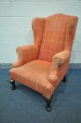 A GEORGE II STYLE WING BACK FIRESIDE ARMCHAIR, later covering in orange tartan upholstery, on