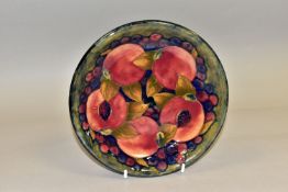 A MOORCROFT POTTERY SHALLOW CIRCULAR BOWL DECORATED IN THE POMEGRANATE PATTERN on a mottled blue