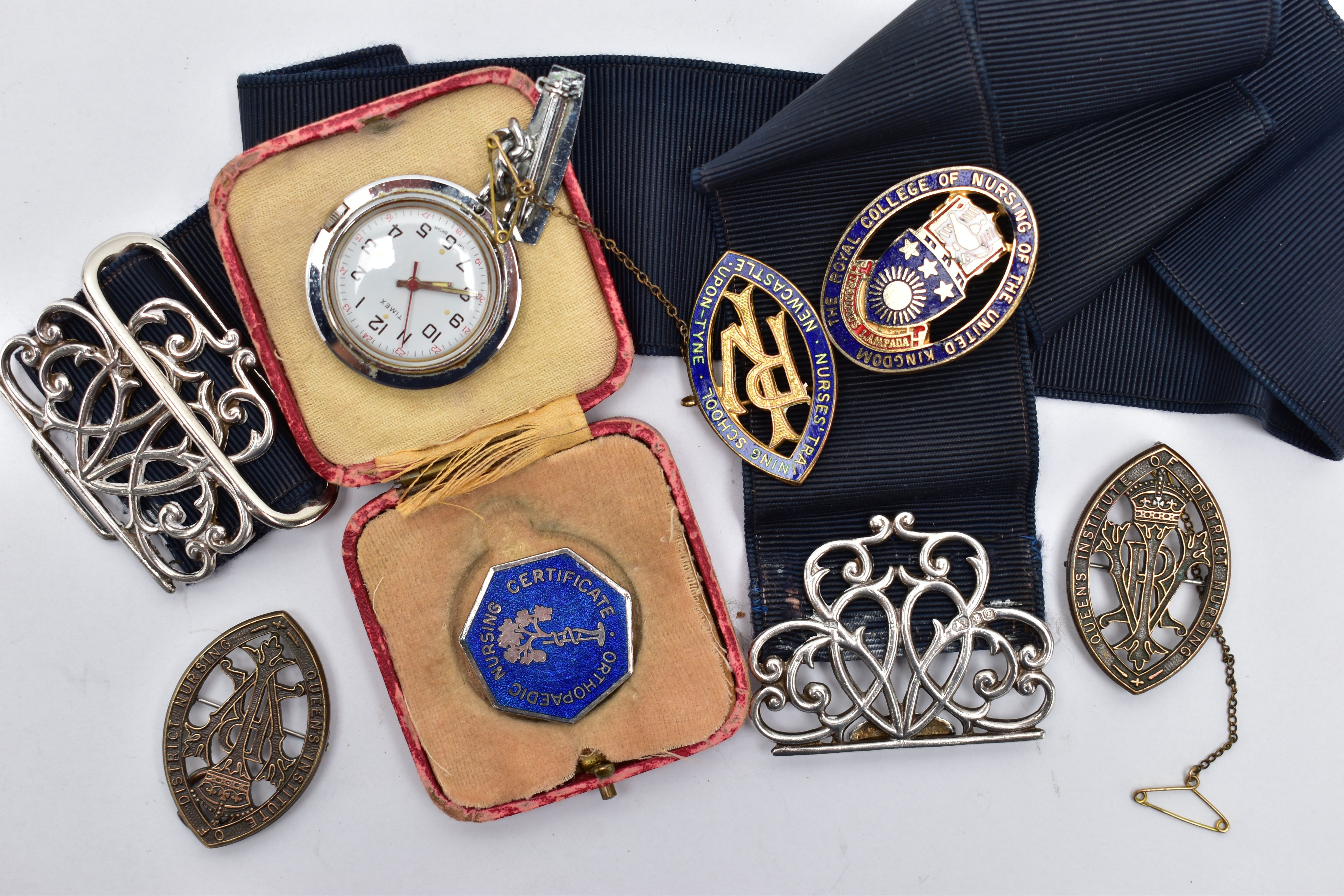 A SILVER NURSES BELT BUCKLE AND NURSING BADGES, a silver open work belt buckle fitted to a stretch