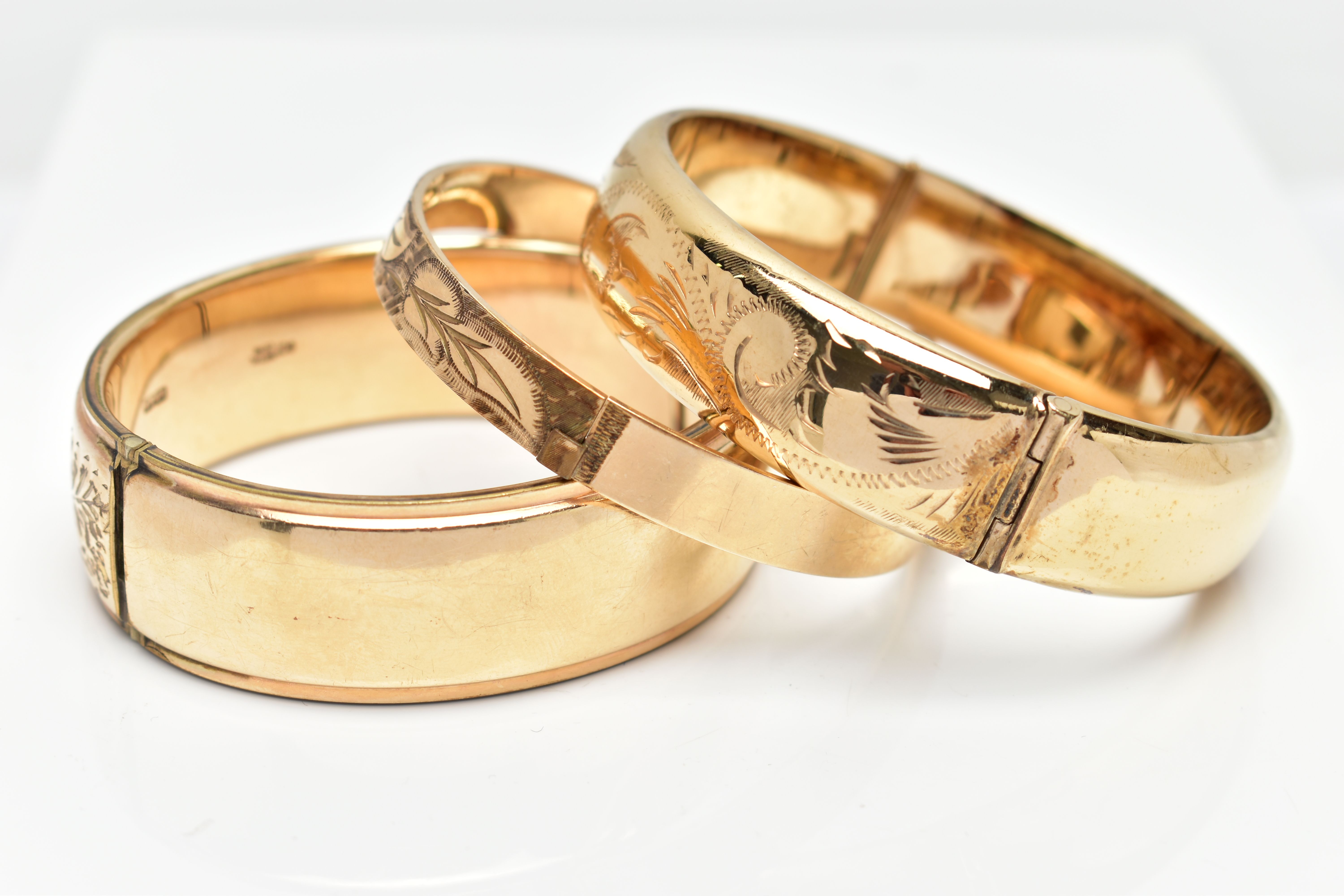 THREE YELLOW METAL HINGED BANGLES, each with a textured and engraved foliate panel design, to the - Image 3 of 3