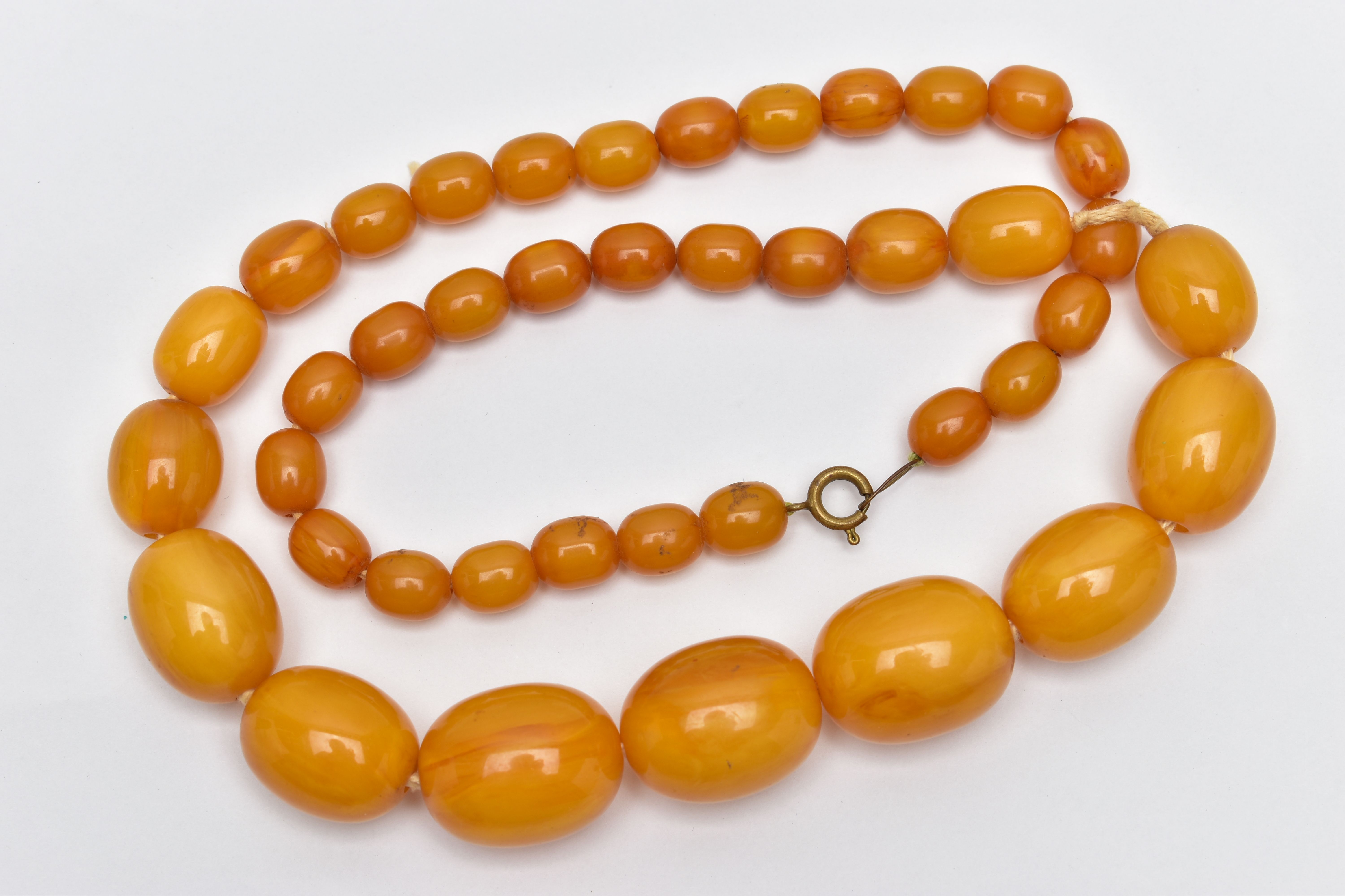 A BAKELITE BEAD NECKLACE, a single row of graduated oval beads, forty one in total, largest