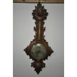 A VICTORIAN BLACK FOREST WHEEL BAROMETER, the frame with leaf scrolls surrounding thermometer and