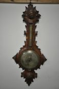 A VICTORIAN BLACK FOREST WHEEL BAROMETER, the frame with leaf scrolls surrounding thermometer and