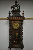 A LATE 19TH CENTURY WALNUT VIENNA WALL CLOCK, with a resin horse pediment, turned pillars to the