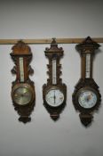 THREE LATE 19TH/EARLY 20TH CENTURY CARVED OAK BAROMETERS, with thermometers, one signed Perry of