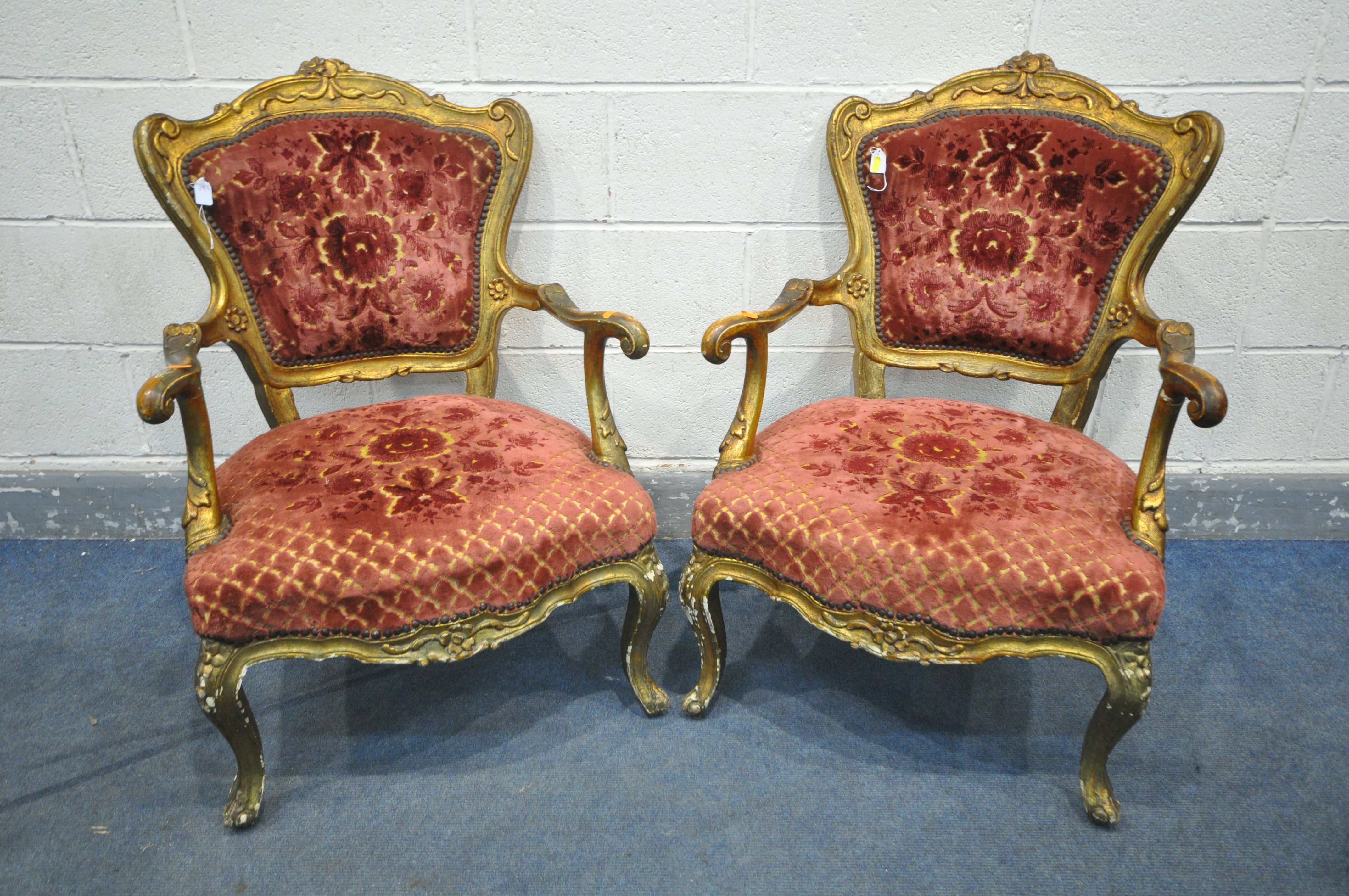 A PAIR OF 19TH CENTURY OR EARLIER LOUIS XV GILT FRAMED OPEN ARMCHAIRS, covered with later