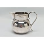 A GEORGE V SILVER JUG OF SQUAT BALUSTER FORM, the S scroll reeded handle on a planished body, makers