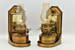 A PAIR OF LATE VICTORIAN BRASS WALL HANGING OIL LAMPS, the shaped rectangular raised back fitted