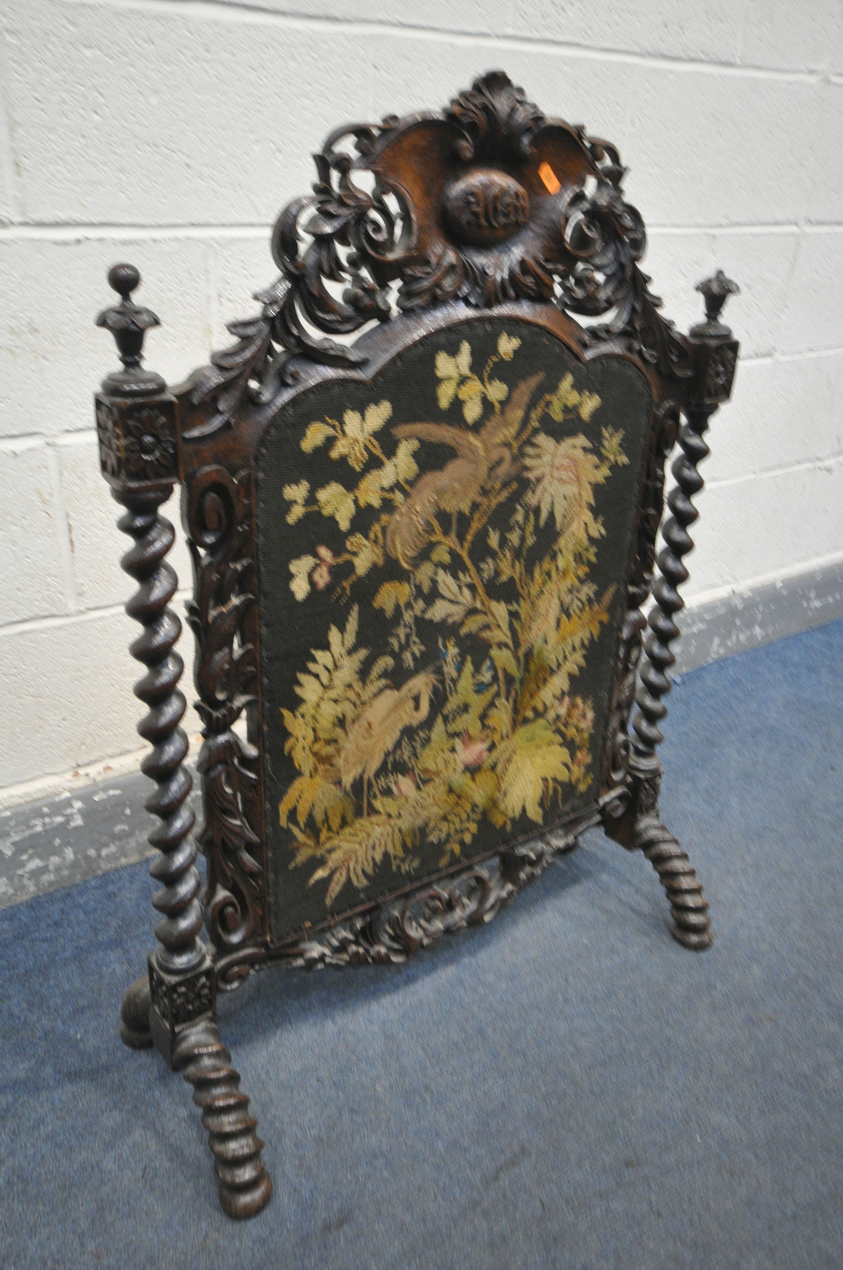 A VICTORIAN CARVED OAK FIRESCREEN, the detailed foliate decorated frame, central lettering reading