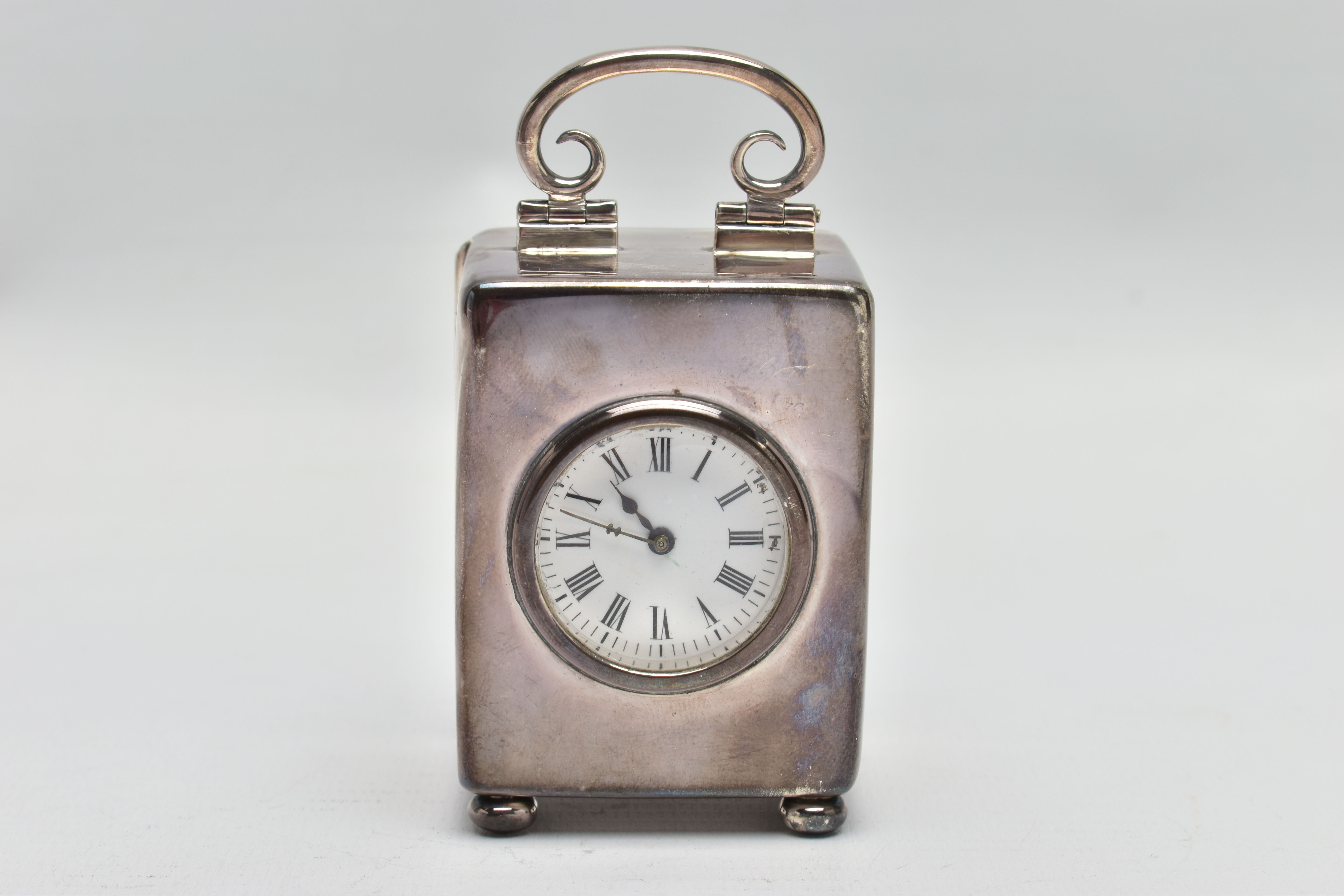 AN EDWARDIAN WILLIAM COMYNS MINIATURE SILVER BOUDOIR CLOCK, the plain case with swing carrying