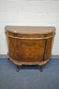 AN EARLY TO MID 20TH CENTURY MAPLE AND CO BURR WALNUT DEMI LUNE SIDE CABINET, with three frieze