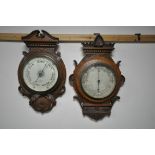TWO LATE 19TH/EARLY 20TH CENTURY CARVED OAK/WALNUT BAROMETERS, one signed with retailer E Saunders