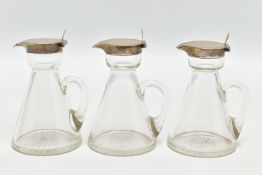 A SET OF THREE EDWARDIAN SILVER MOUNTED CONICAL GLASS WHISKY NOGGINS, with star cut bases, the