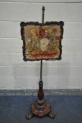 A VICTORIAN WALNUT POLE SCREEN, the shaped frame with a glass panel enclosing a needlework