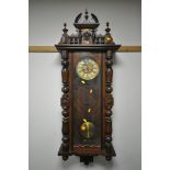 A LATE 19TH CENTURY WALNUT VIENNA WALL CLOCK, the shaped surmount, above turned pillars flanking a