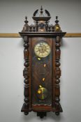 A LATE 19TH CENTURY WALNUT VIENNA WALL CLOCK, the shaped surmount, above turned pillars flanking a