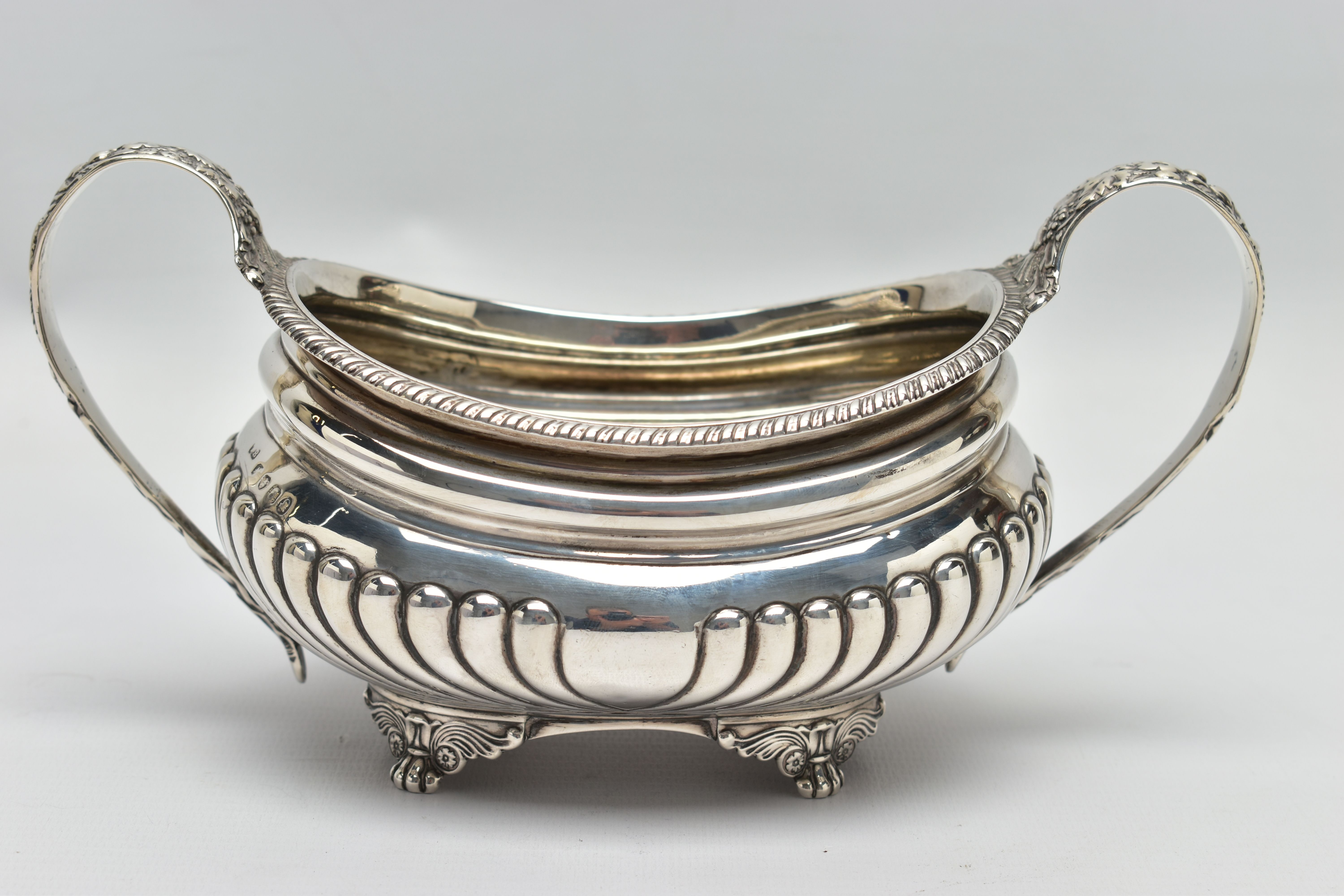 A GEORGE III SILVER TWIN HANDLED SUGAR BOWL OF OVAL FORM, gadrooned rim, cornucopia cast C scroll