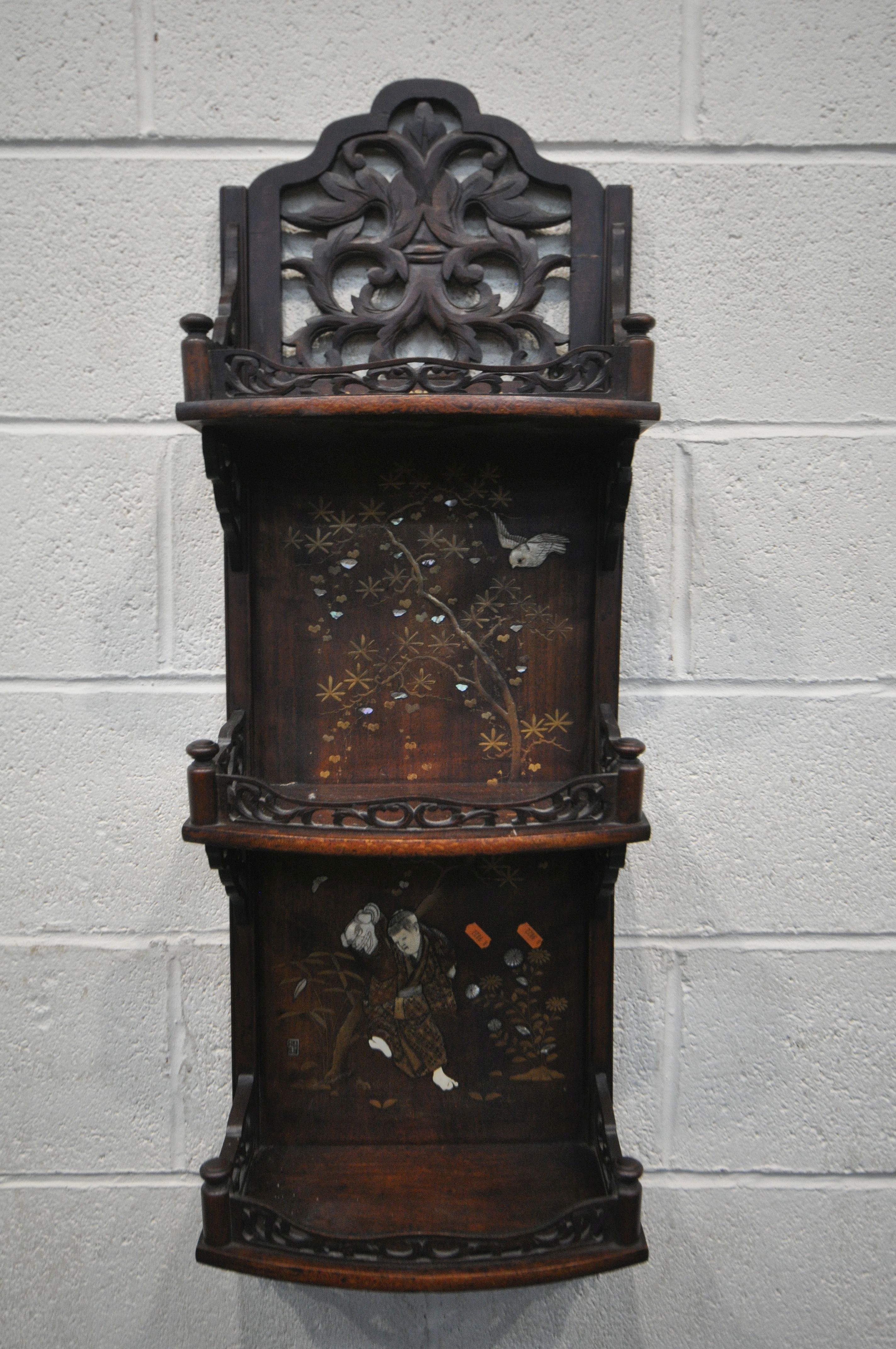 A 20TH CENTURY HARDWOOD JAPANNED WALL SHELF, made up of three shelves, with open foliate fretwork