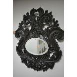 A HEAVILY CARVED WALL MIRROR, with use of antique timbers, the large frame with scrolled foliate