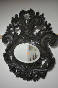 A HEAVILY CARVED WALL MIRROR, with use of antique timbers, the large frame with scrolled foliate