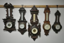 FIVE LATE 19TH/EARLY 20TH CENTURY CARVED WOOD ANEROID BAROMETERS, with thermometers, max height 70cm