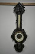 A LATE 19TH/EARLY 20TH CENTURY CARVED OAK ANEROID BAROMETER, with a thermometer, the frame carved