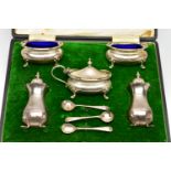 A CASED GEORGE V WALKER & HALL SILVER EIGHT PIECE CRUET SET OF SHAPED RECTANGULAR FORM, wavy rims,