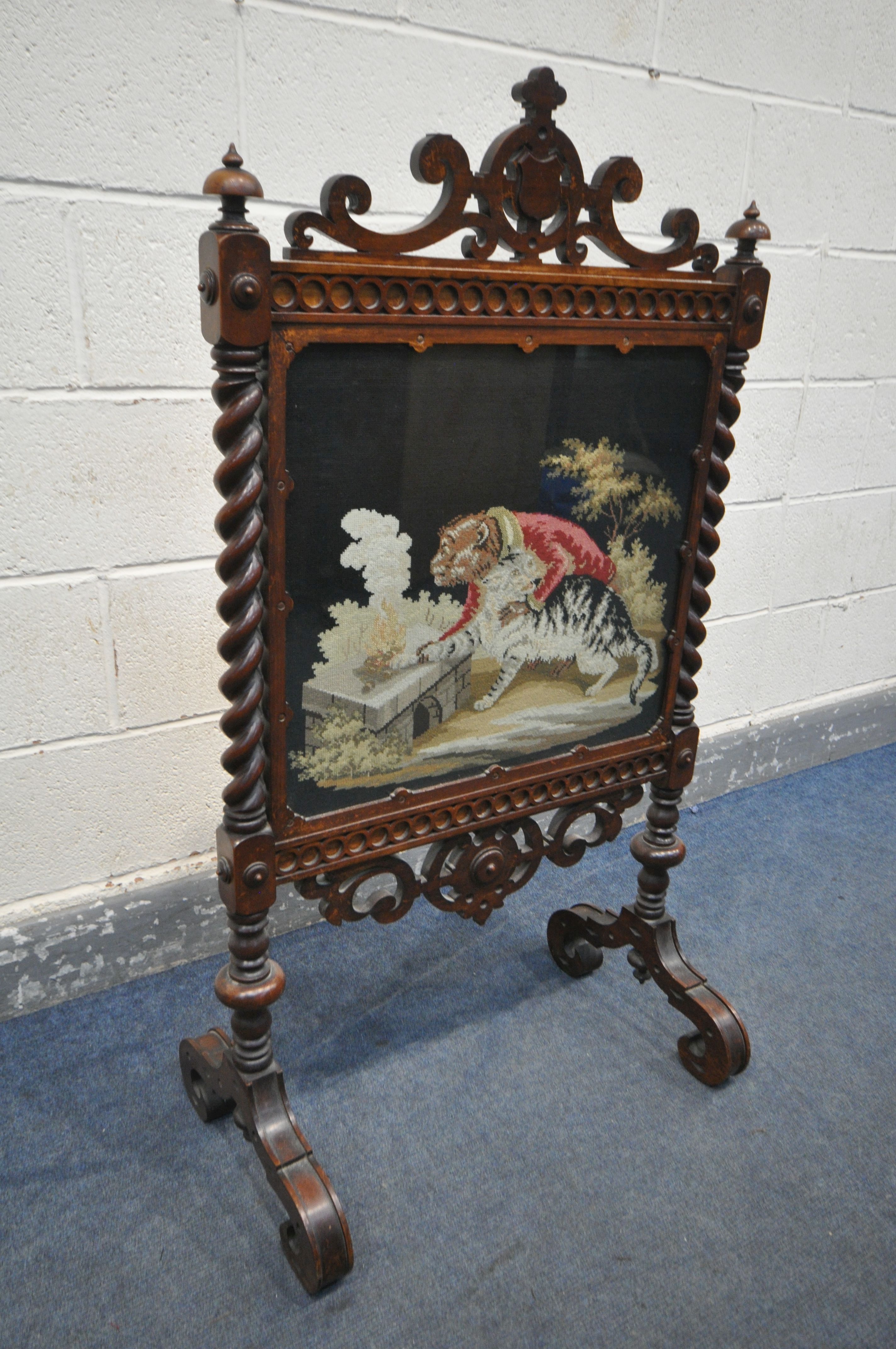 A VICTORIAN WALNUT FIRESCREEN, with open scrolls and central shield, turned finials, barley twist